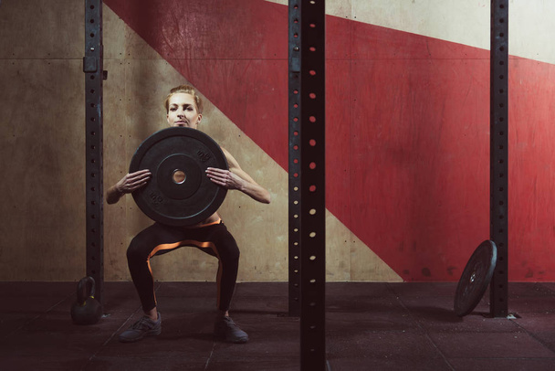 Gym. She squats with a barbell - Φωτογραφία, εικόνα