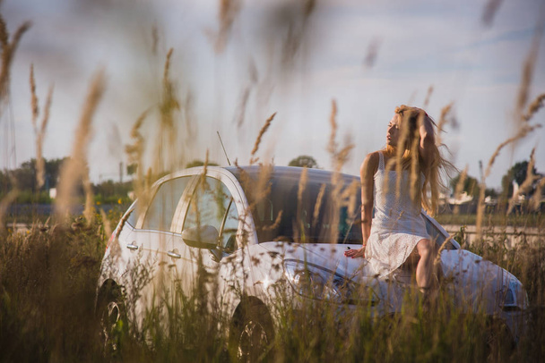 A girl sits on the hood of a car - Foto, Imagen