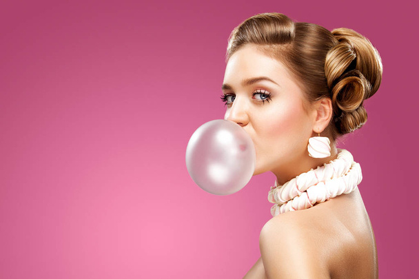 Beautiful blonde woman blowing pink bubble gum. Fashion portrait. - Foto, afbeelding