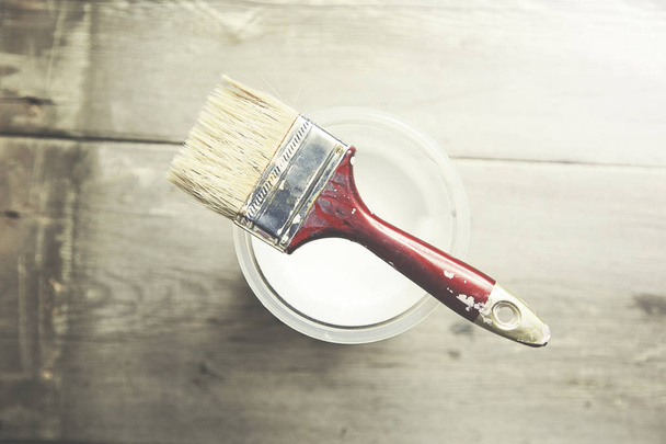 paint brush on can lying on wooden table - Foto, imagen