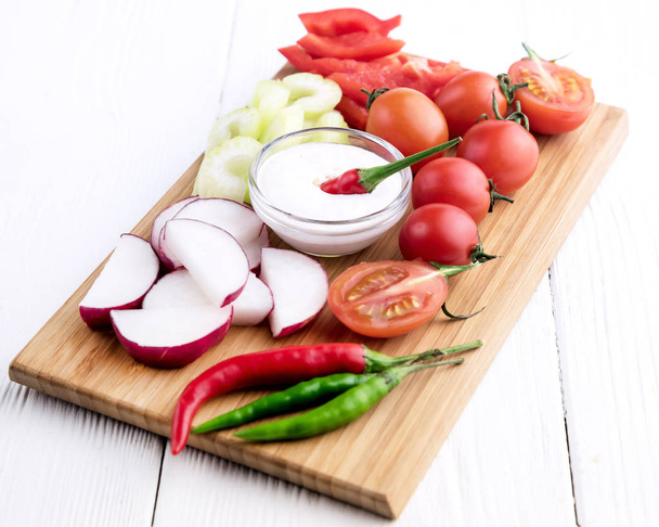 Chopped vegetables served on wooden kitchen board - Photo, image
