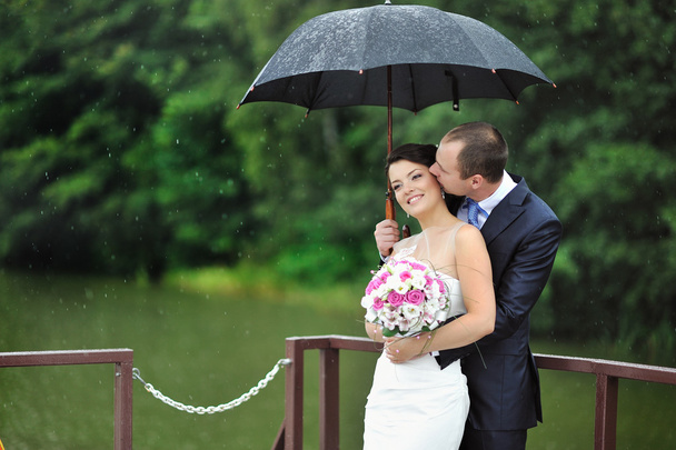 An excited wedding couple in a rainy day - Photo, Image