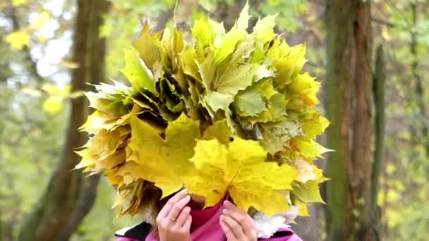 Modèle avec couronne sur sa tête envoie baiser et joue avec des feuilles sur la forêt
. - Séquence, vidéo