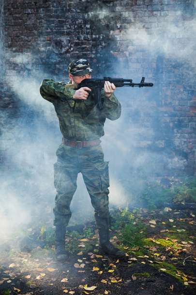 Soldato o miliziano in camuffamento con fucile d'assalto AK combattendo in rovina
 - Foto, immagini