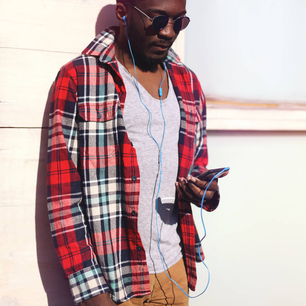 Fashion portrait young african man listens to music on the smart - Фото, изображение
