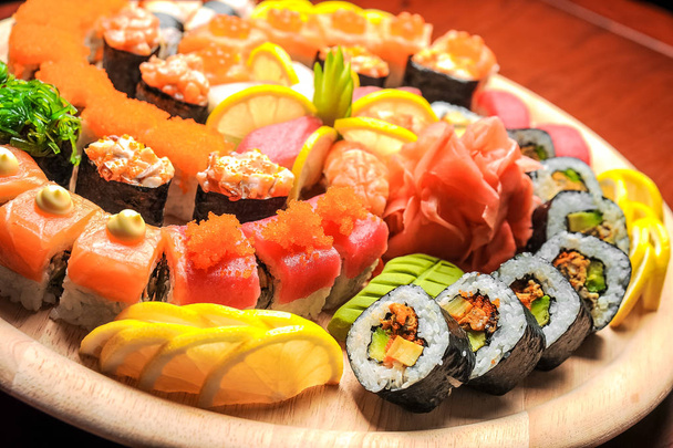Суши и булочки с рыбой, подаваемые на деревянном столе
 - Фото, изображение