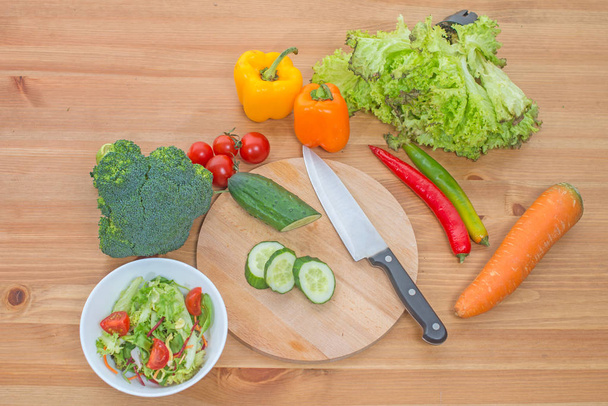 Chopped salad and whole fresh vegetables on wooden table. Top view. - Foto, afbeelding