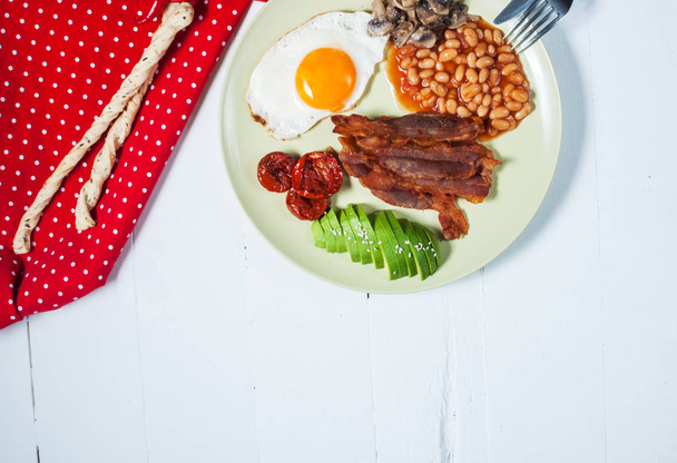 Englisches Frühstück mit Speck, Spiegelei, Bohnen, Champignons, Avocado - Foto, Bild