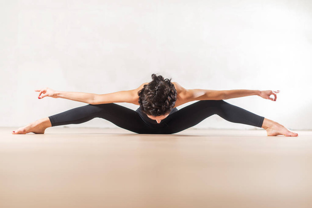 Νεαρή χορεύτρια Καυκάσιος κάνει άσκηση stretching σπονδυλική στήλη και τα πόδια - Φωτογραφία, εικόνα