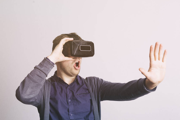 Молодий чоловік в окулярах віртуальної реальності в повсякденному одязі дивиться вперед
.  - Фото, зображення