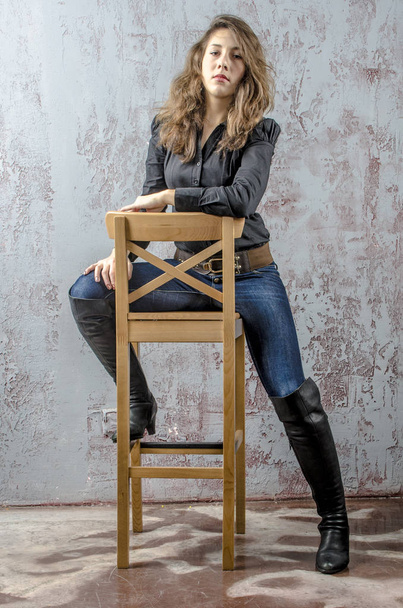  Young girl with curly hair in a black shirt, jeans and high boots cowboy western style - Φωτογραφία, εικόνα