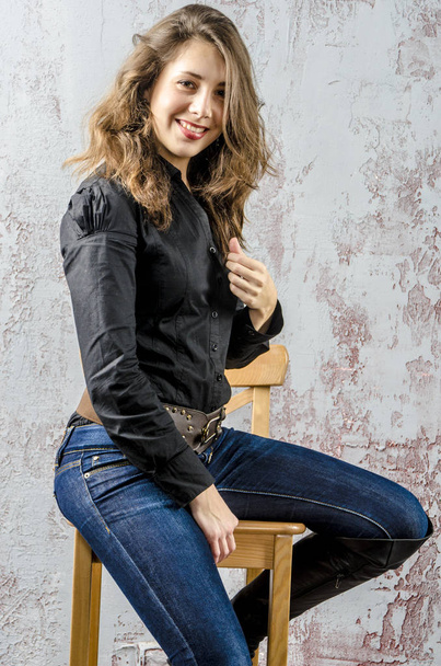  Young girl with curly hair in a black shirt, jeans and high boots cowboy western style - Photo, image