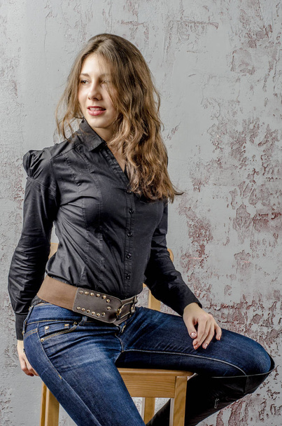  Young girl with curly hair in a black shirt, jeans and high boots cowboy western style - Фото, зображення