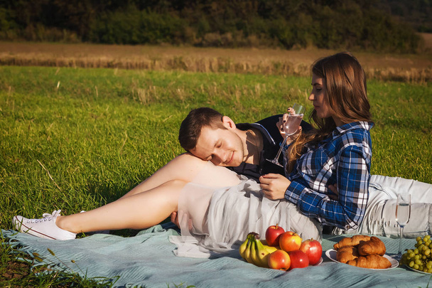 Woman hugging guy. they drinking wine picnic in the field - Фото, изображение