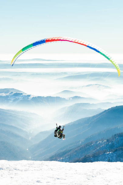 Paragliders launched into air from snowy slope of a mountain - Photo, Image