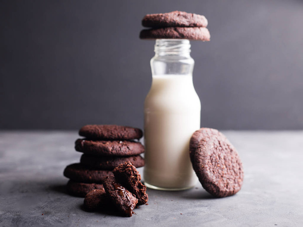biscotti con gocce di cioccolato con una bottiglia di latte su sfondo grigio
 - Foto, immagini