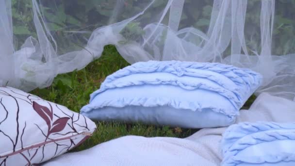 Blauwe kussens en witte transparante stof in het park. Mooie bruiloft decor - Video
