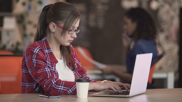 Mujer intelectual escribiendo en el ordenador portátil en la cafetería, freelancer trabajando en un nuevo proyecto
 - Metraje, vídeo