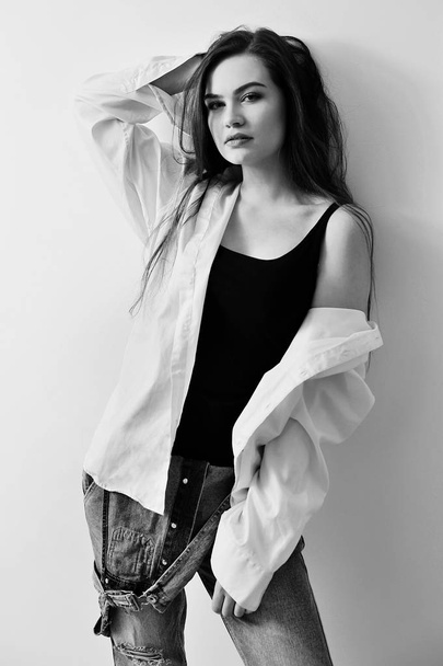 Jovem modelo de moda atraente europeu está posando em jeans macacão e camisa
 - Foto, Imagem