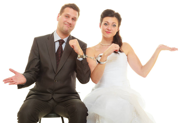 Bride and groom in handcuffs wearing wedding outfits - Фото, изображение