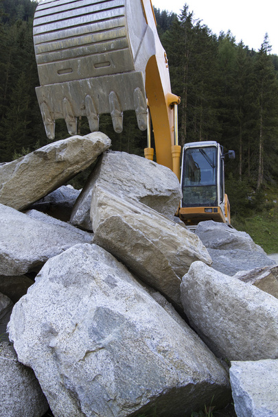 Excavadora con grandes rocas
 - Foto, Imagen