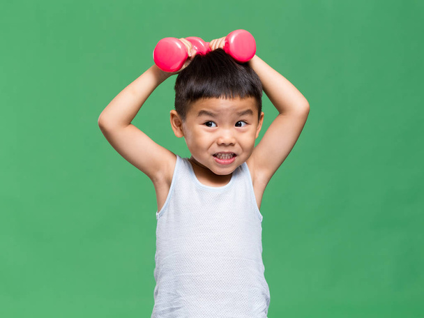 Little boy holding up dumbbell - Foto, immagini