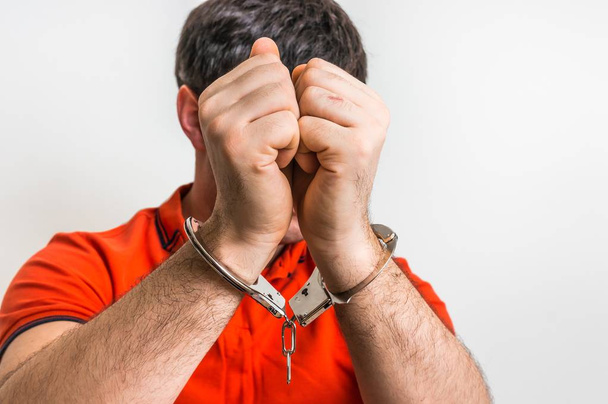 Заарештований чоловік в наручниках сховав обличчя
 - Фото, зображення