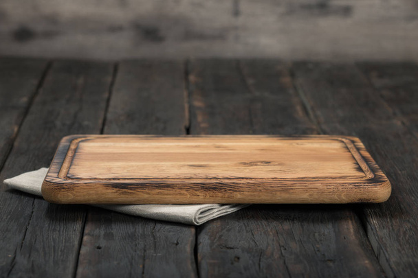 Empty cutting board with cloth napkin on wooden table - Fotó, kép