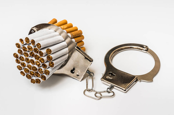Cigarettes and handcuffs - smoking addiction concept - Фото, изображение