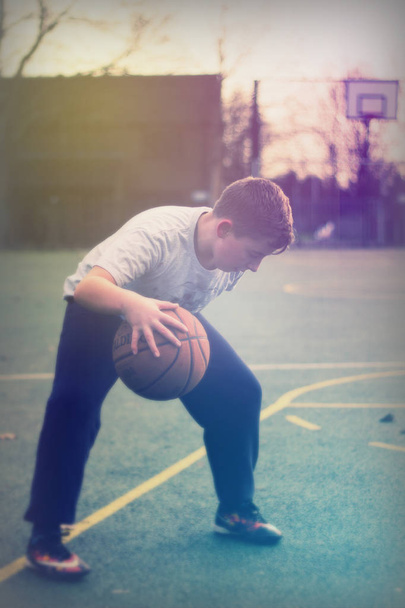Child playing basketball in a local park - Foto, imagen