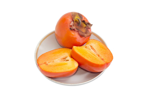 One whole and cut in half of persimmon on saucer - Photo, Image