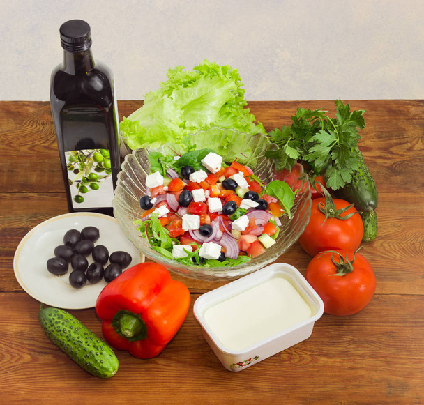 Salade grecque parmi les ingrédients pour sa cuisson sur une surface en bois
 - Photo, image