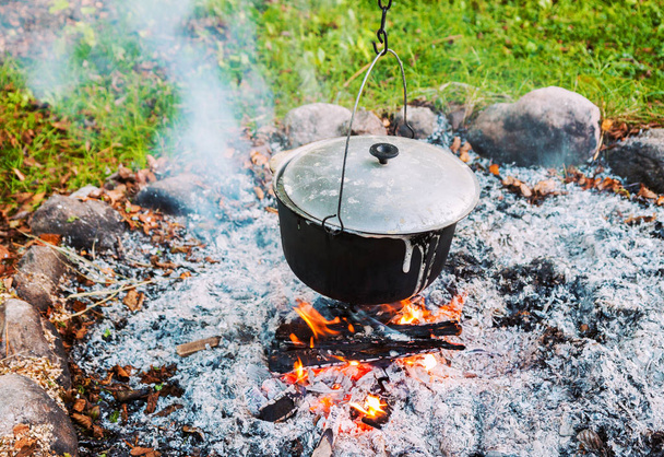 Metal pot over a campfire outdoors - Фото, изображение