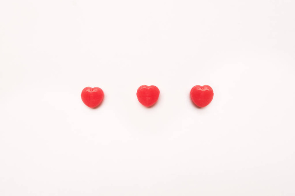 üç kırmızı Valentine's gün kalp şekli şeker hatta beyaz kağıt arka plan. Aşk kavramı. Minimalizm tarzı. Knolling Üstten Görünüm. - Fotoğraf, Görsel