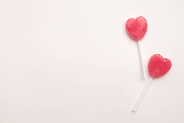 two Pink Valentine's day heart shape lollipop candy on empty white paper background. Love Concept. Knolling top view. Minimalism colorful hipster style. - Фото, изображение