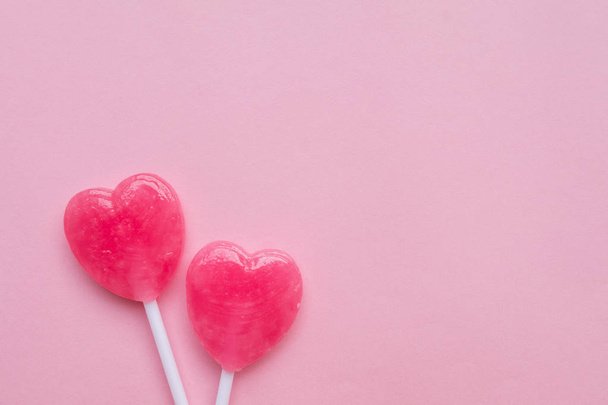 two Pink Valentine's day heart shape lollipop candy on empty pastel pink paper background. Love Concept. Knolling top view. Minimalism colorful hipster style. - Фото, изображение