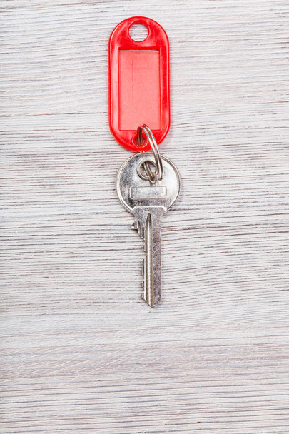 clé avec porte-clés blanc rouge sur table en bois
 - Photo, image