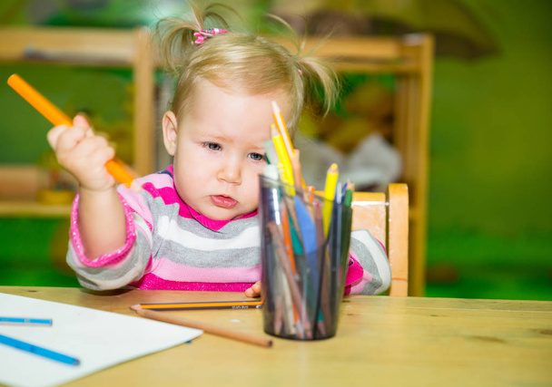 Adorable child girl drawing with colorful pencils in nursery room. Kid in kindergarten in Montessori preschool class. - 写真・画像
