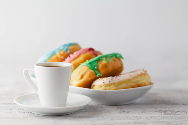 Few colorfull donuts lay on plate with cup of espresso - Foto, Imagen