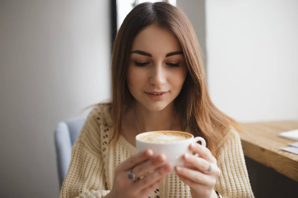 Lovely woman blowing on cup of coffee in a cafe - Foto, Bild