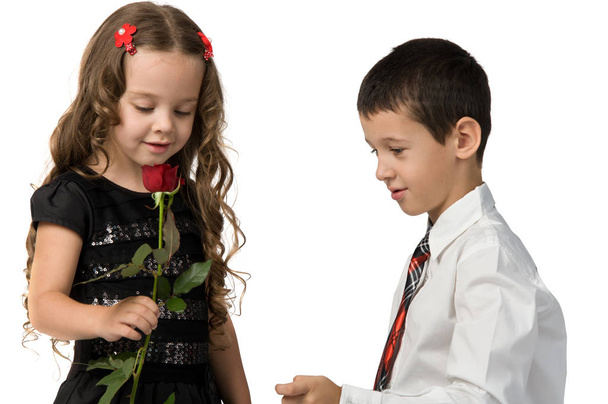 маленький хлопчик дає червону троянду дівчинці
. - Фото, зображення