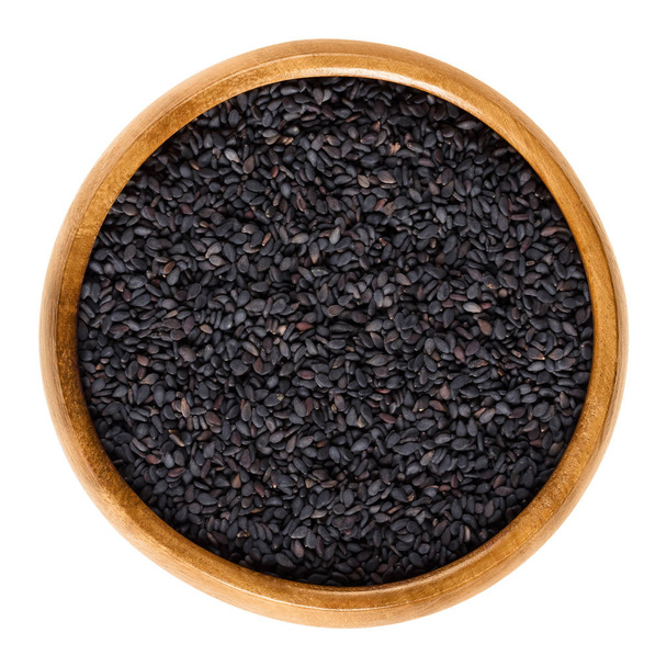 Black sesame seeds, also benniseed, in wooden bowl - Φωτογραφία, εικόνα