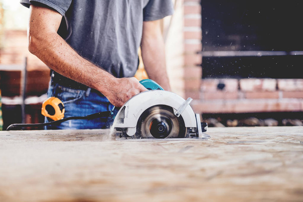 Construction worker, industrial carpenter using circular miter saw for cutting boards - Fotoğraf, Görsel