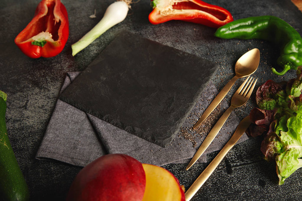 Vegetables around a black slate cheese board - Фото, зображення