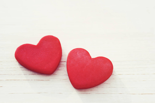 Two red hearts on a wooden white background, soft focus. Romantic card.  - Zdjęcie, obraz