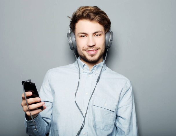 young man wearing headphones and holding mobile phone - Fotoğraf, Görsel