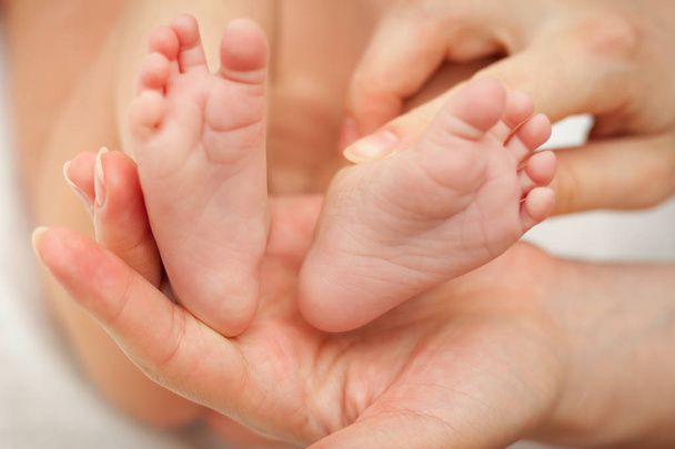 Pequenos pés de bebê recém-nascido que segurar em sua mão mães
. - Foto, Imagem