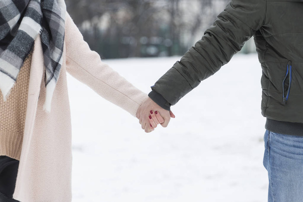 Couple holding hands walking on the snow - Фото, изображение