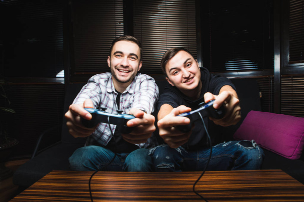 Two young happy men playing video games - 写真・画像