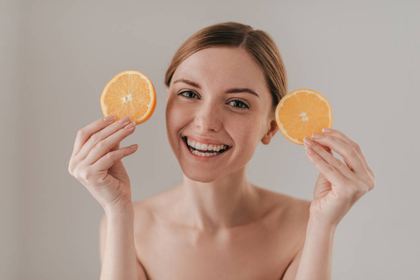 Hermosa mujer sosteniendo rodajas de naranja
 - Foto, imagen
